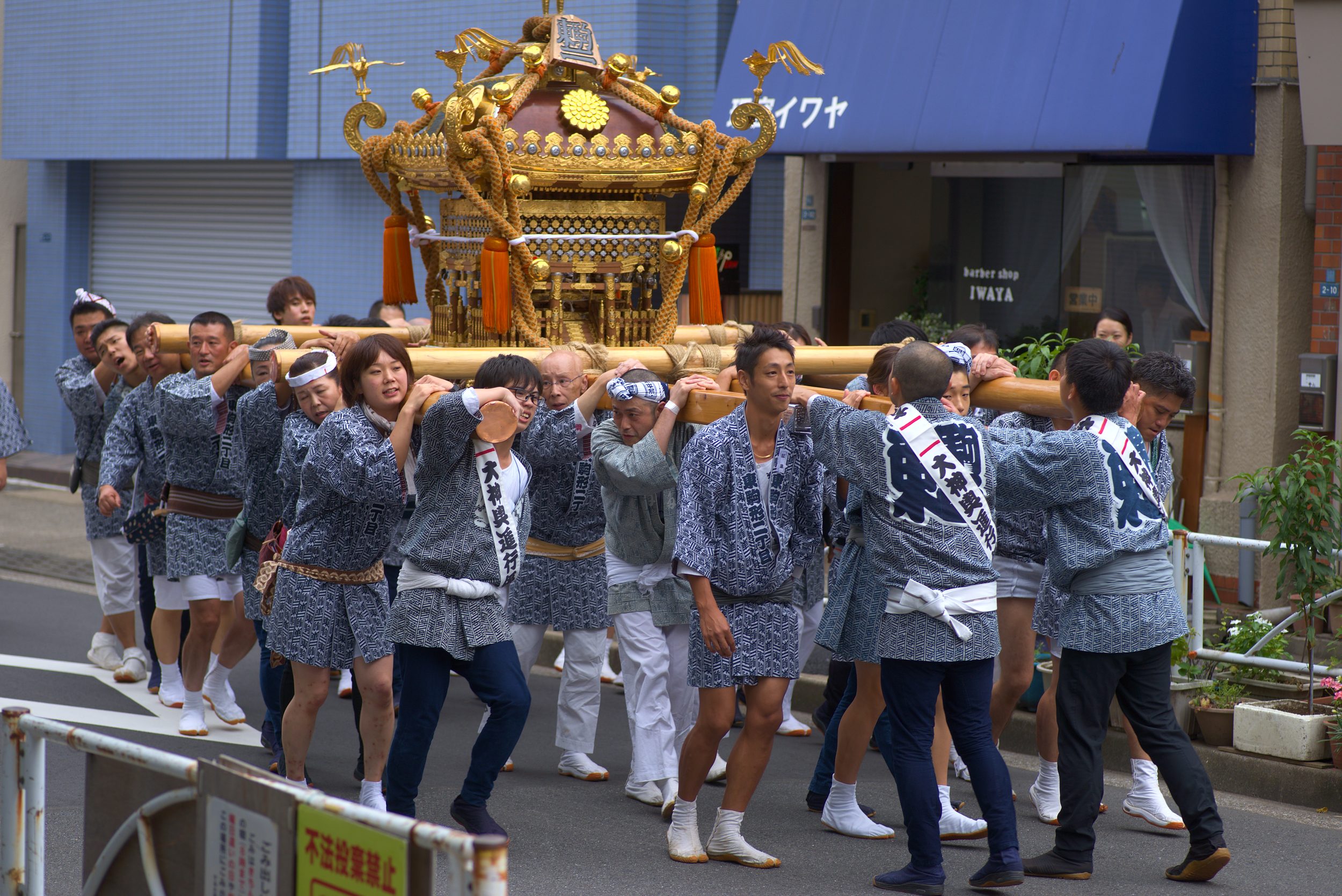 25 young people corrying a mikoshi and chanting