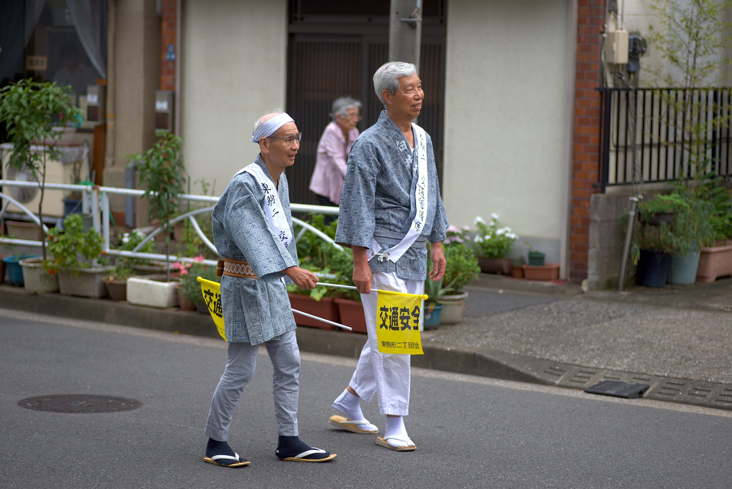 Two old man walking on the street with small yellow flags