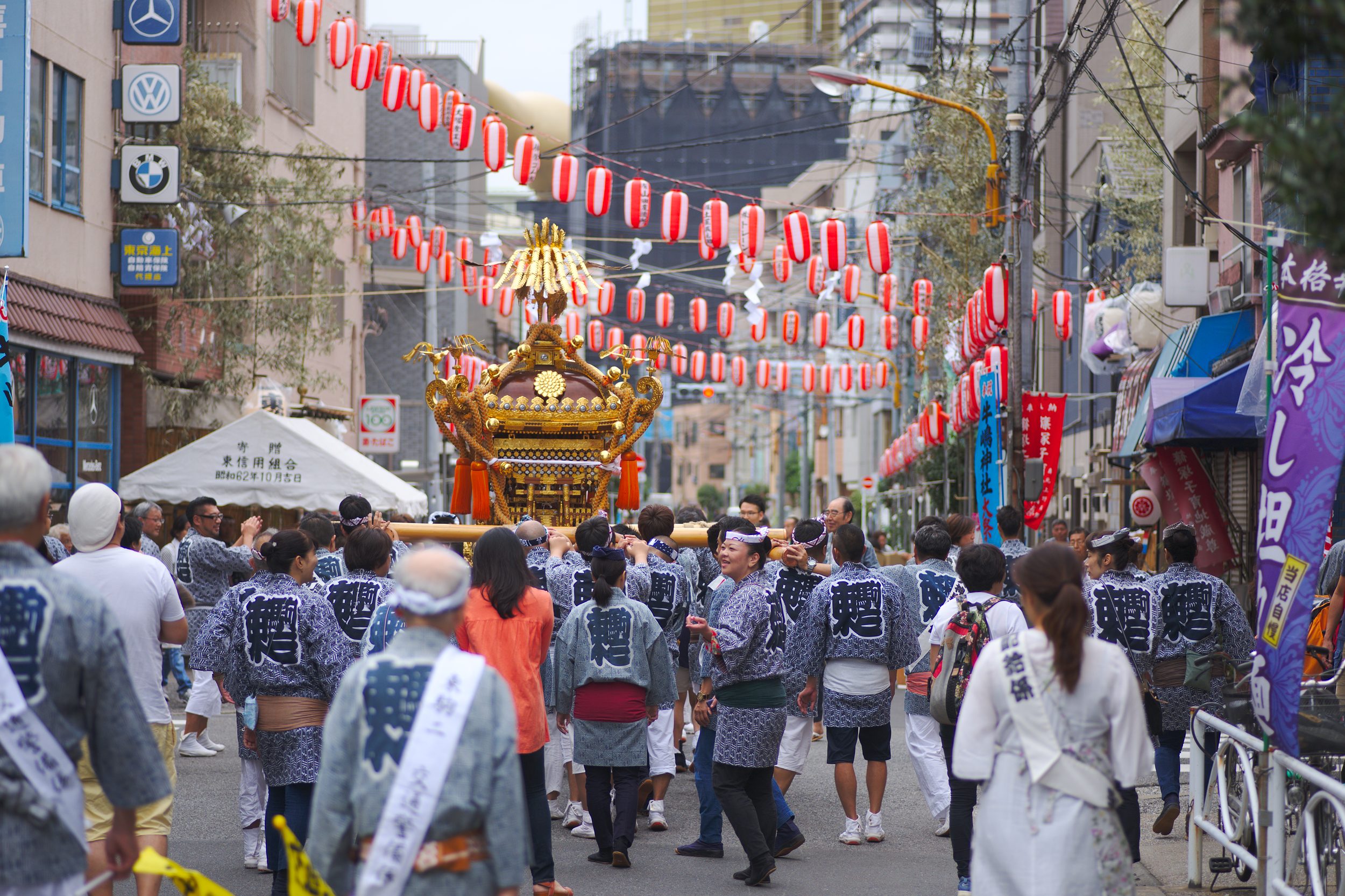 People carrying a mikoshi, red lamps hanging over them