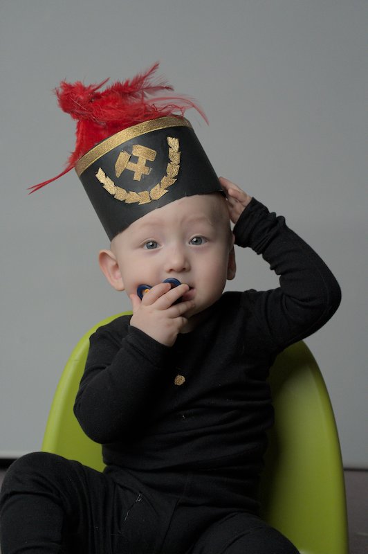 Baby with coal miner hat on green chair