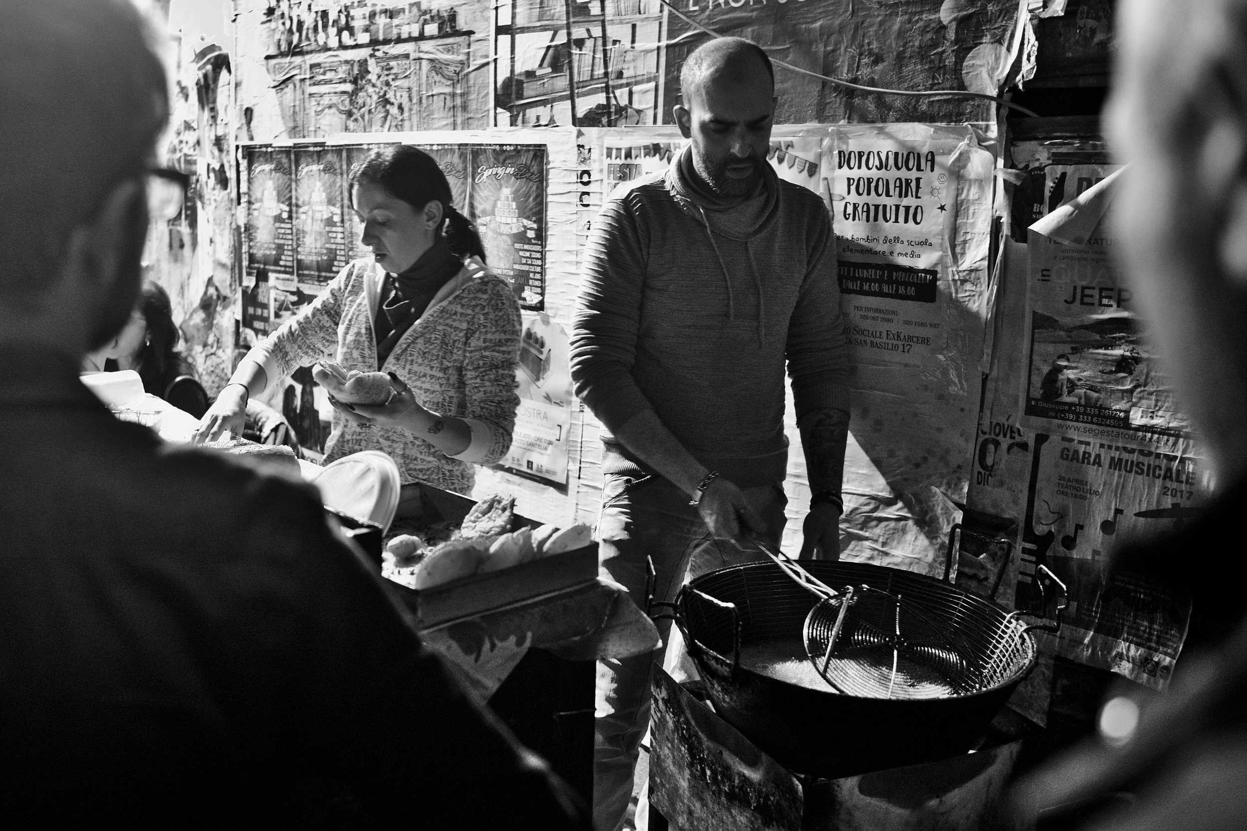 Woman preparing a bun while man deepfrying