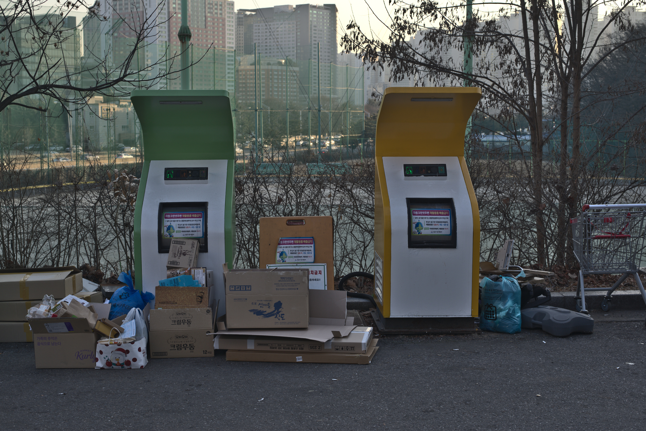 two trash machines with a lot of recycling trash around